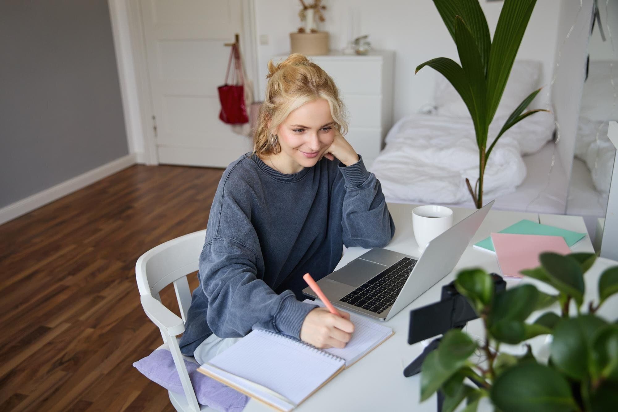 portrait-smiling-beautiful-blond-woman-writing-down-notes-doing-homework-studying-from-home-doing_1258-254363